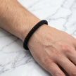 Black beaded bracelet on a wrist against a marble background